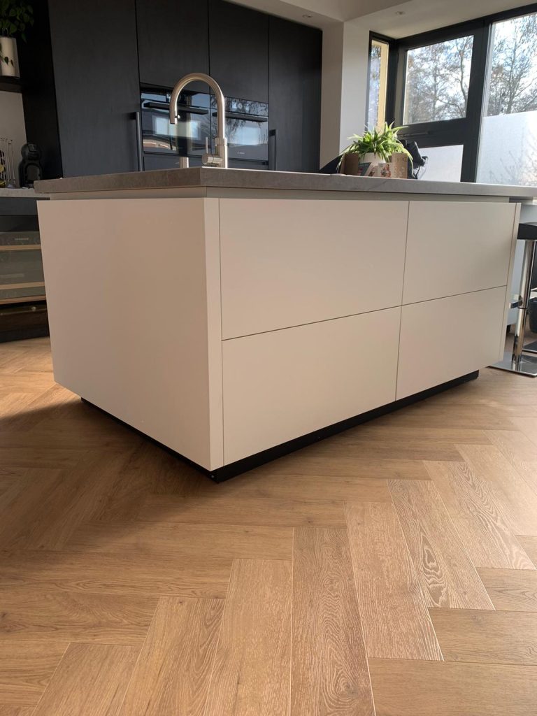 Moderne keuken met kookeiland en houten vloer.