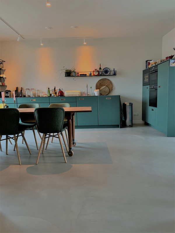 Moderne eetkeuken met houten tafel en groene kasten.