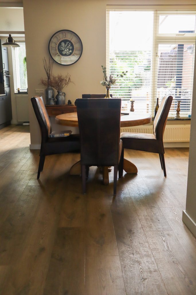 Eettafel in lichte woonkamer met houten vloer.