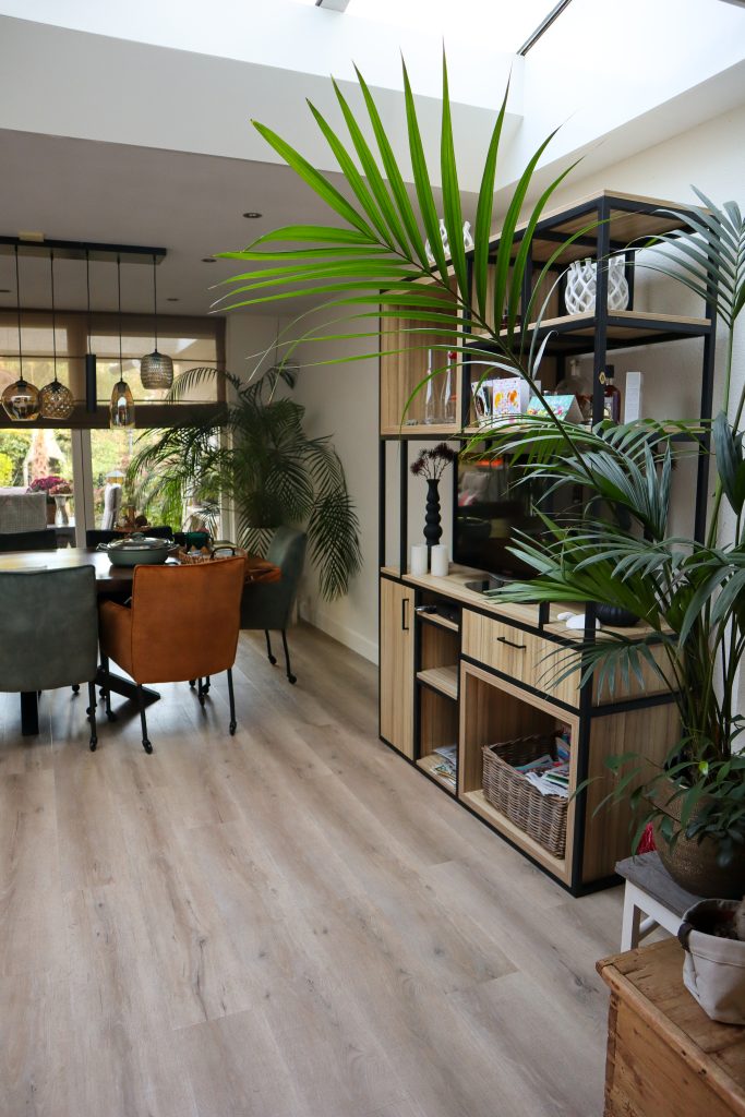 Moderne eetkamer met planten en houten vloer.